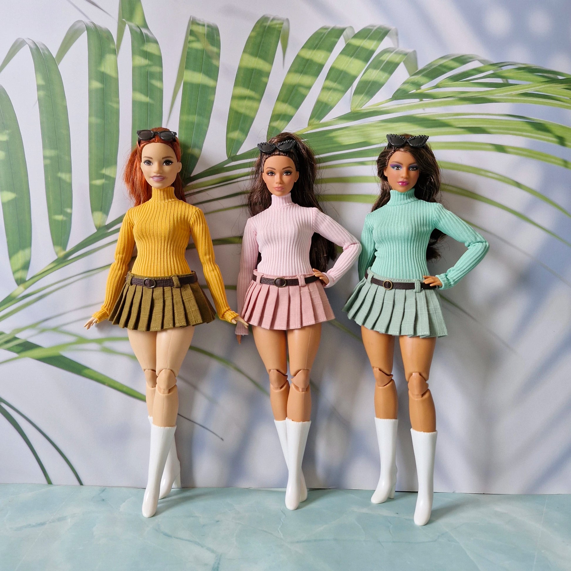 Three Curvy Barbie dolls modeling mix and match ribbed turtleneck sweaters and pleated skirts in yellow pink and green