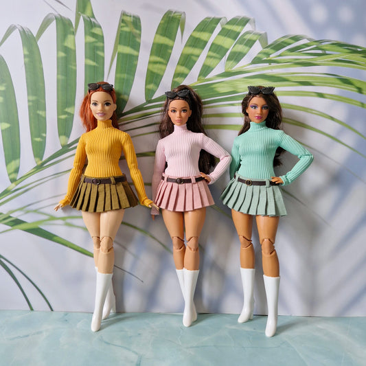 Three Curvy Barbie dolls modeling mix and match ribbed turtleneck sweaters and pleated skirts in yellow pink and green