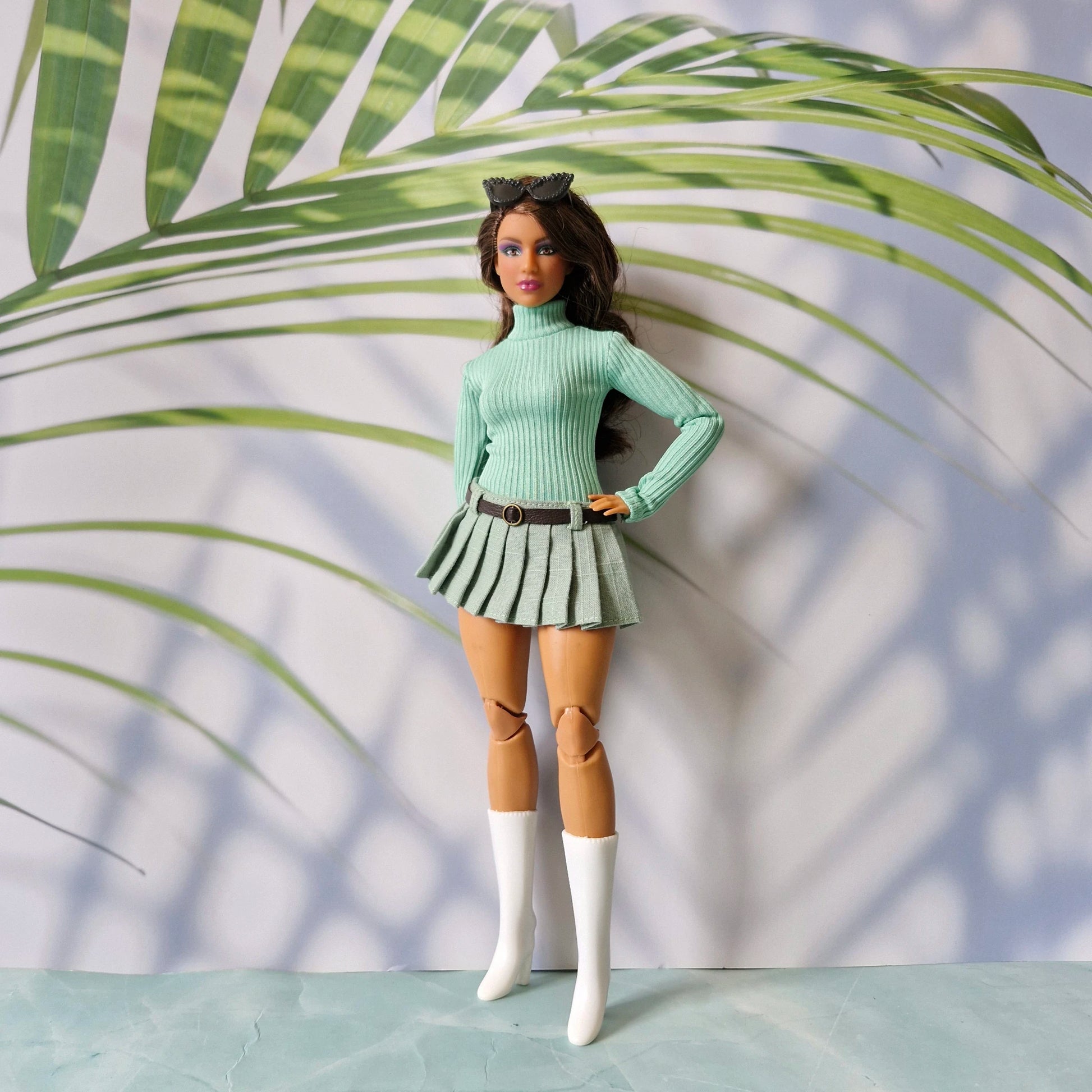 Curvy fashion doll posing in a mint green ribbed long sleeve sweater and matching light green pleated skirt