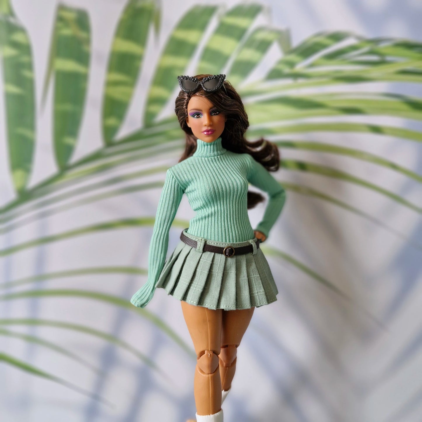 Curvy fashion doll posing in a mint green ribbed long sleeve sweater and matching light green pleated skirt