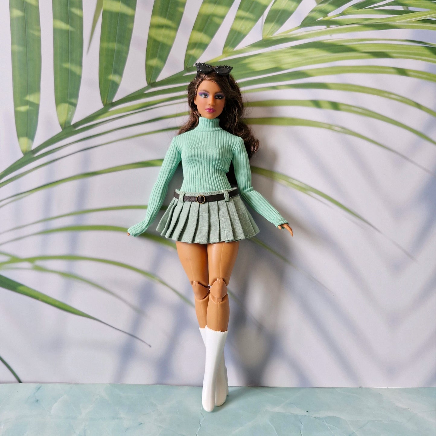 Curvy fashion doll posing in a mint green ribbed long sleeve sweater and matching light green pleated skirt