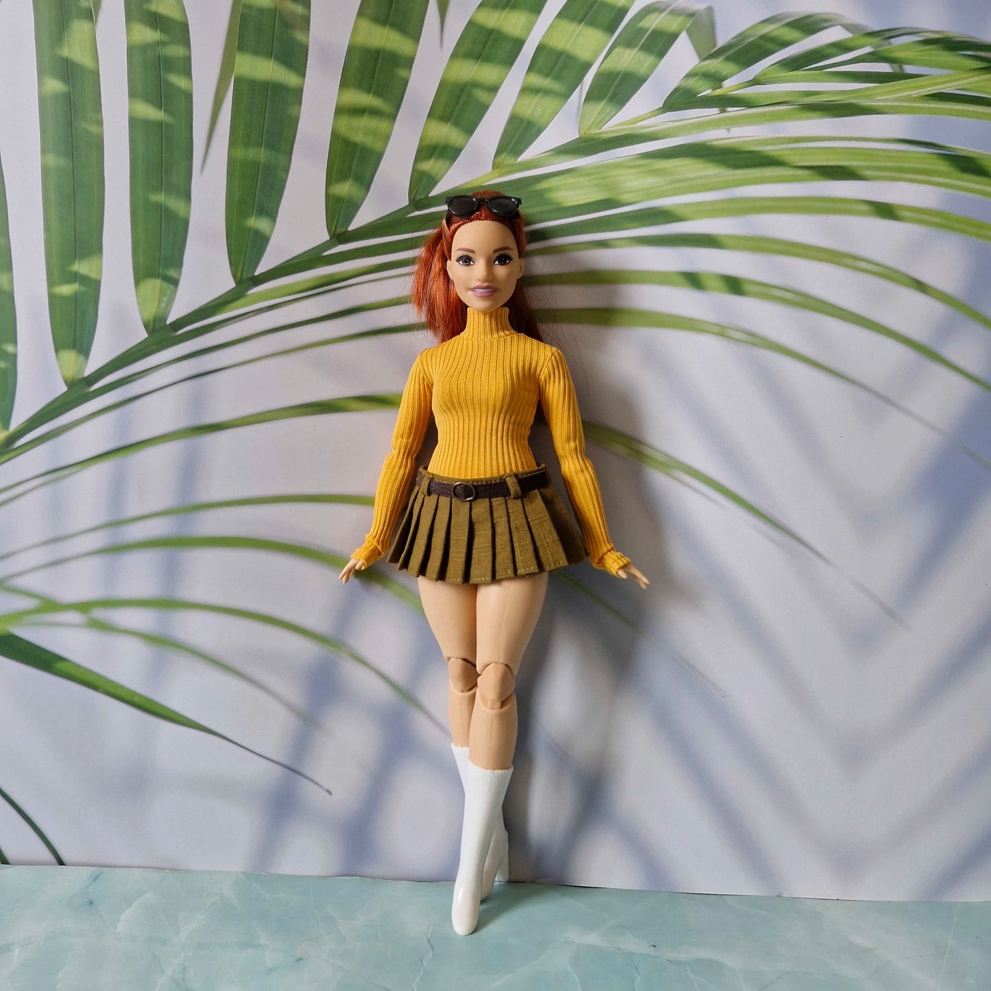 Redhead Curvy Barbie doll wearing a mustard yellow ribbed turtleneck sweater and olive green pleated mini skirt