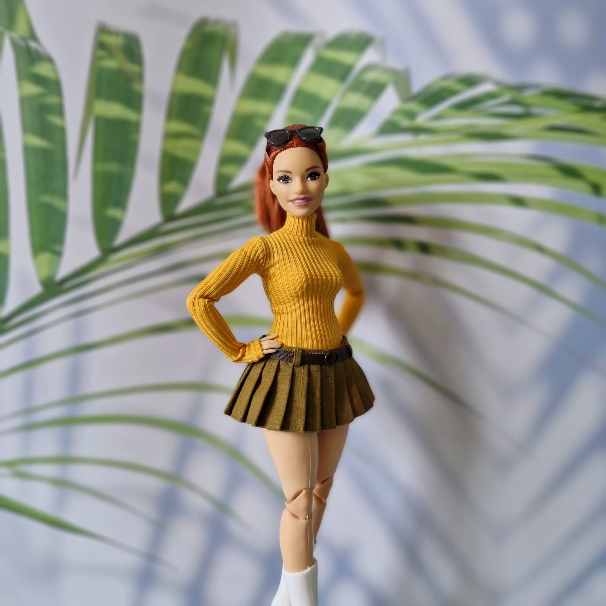 Redhead Curvy Barbie doll wearing a mustard yellow ribbed turtleneck sweater and olive green pleated mini skirt