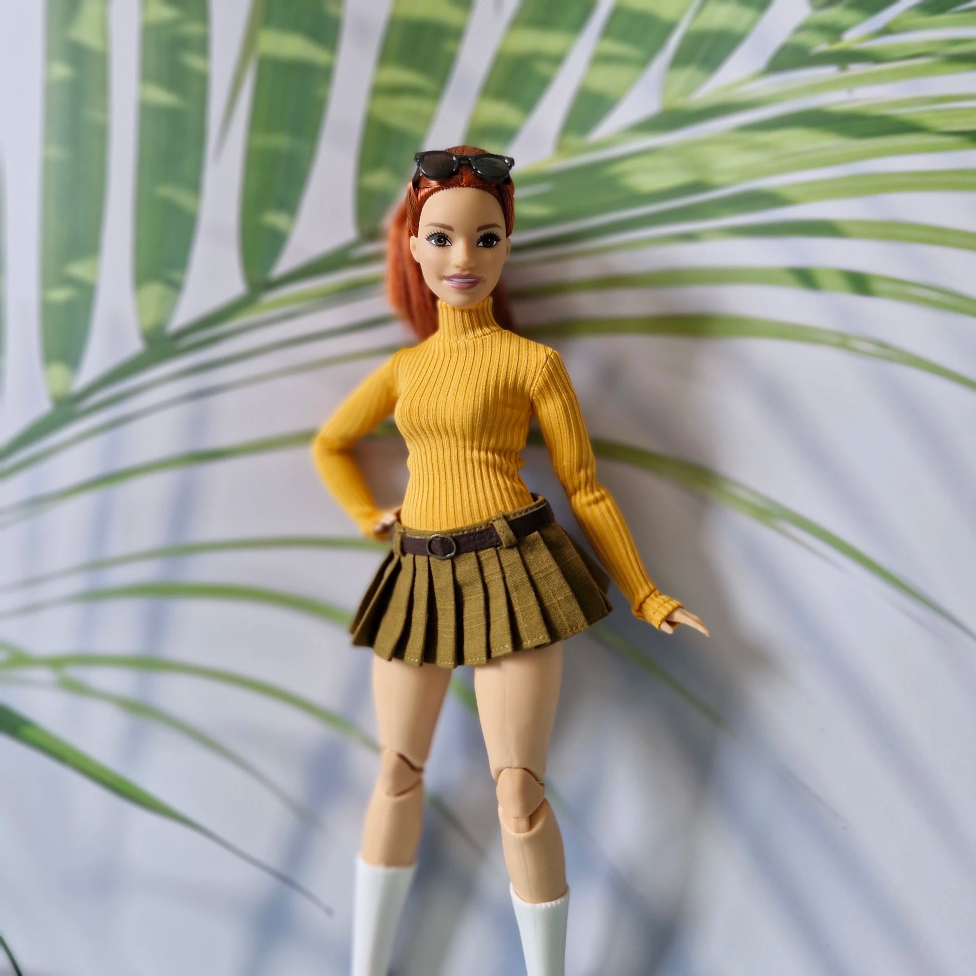 Redhead Curvy Barbie doll wearing a mustard yellow ribbed turtleneck sweater and olive green pleated mini skirt