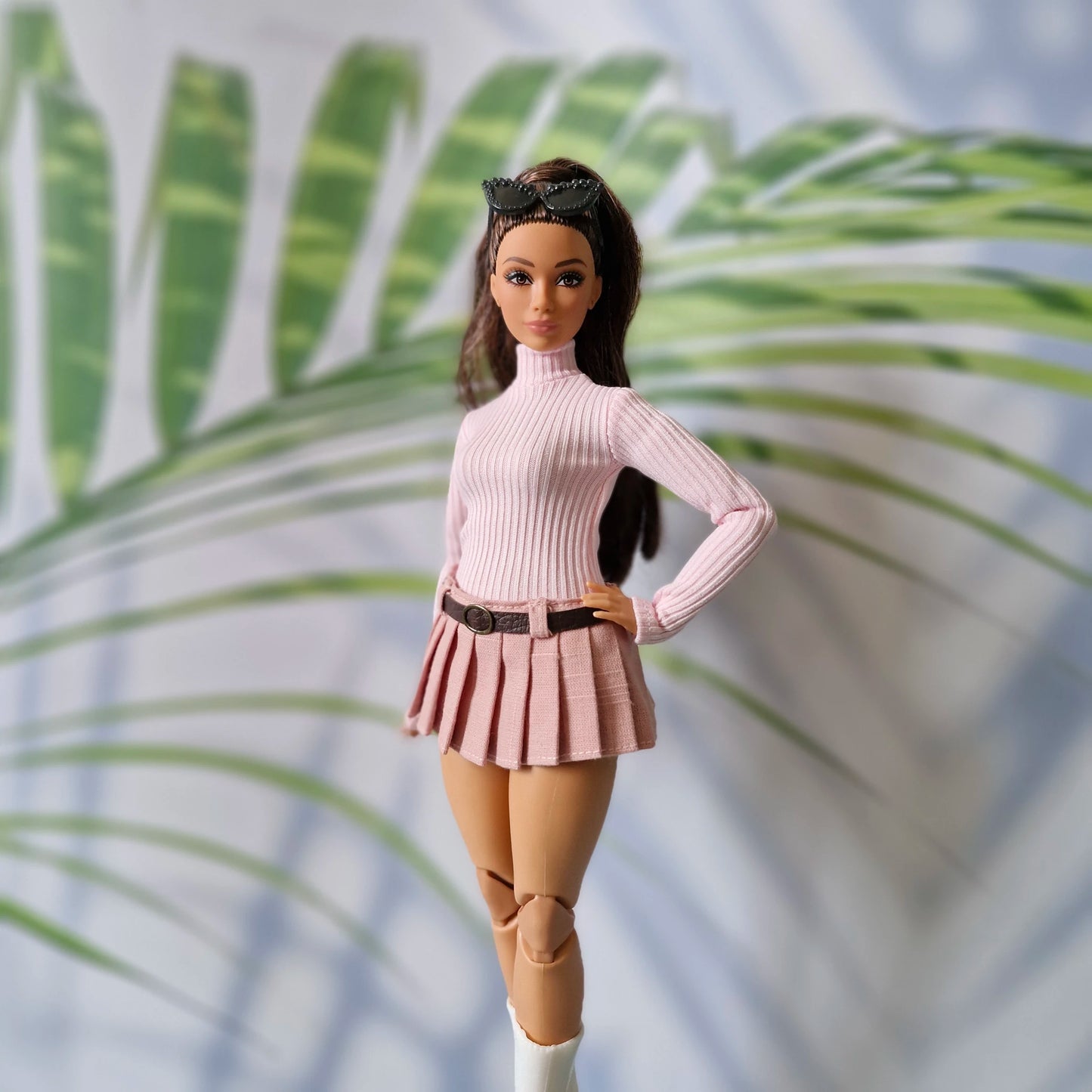 Brunette Curvy Barbie doll modeling a baby pink long sleeve turtleneck and dusty pink pleated skirt with belt