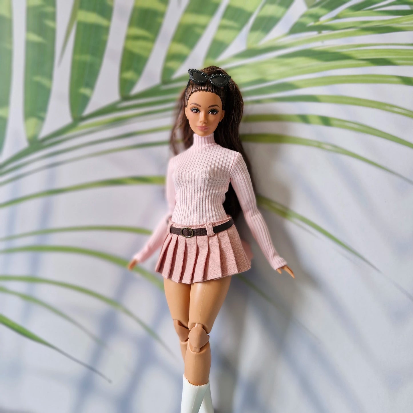 Brunette Curvy Barbie doll modeling a baby pink long sleeve turtleneck and dusty pink pleated skirt with belt