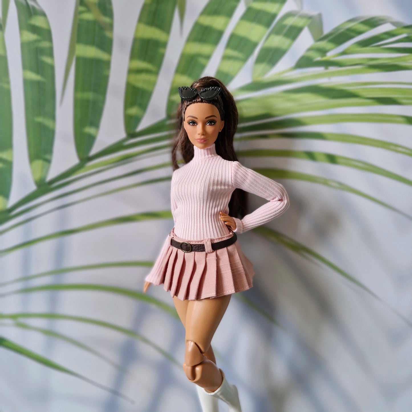 Brunette Curvy Barbie doll modeling a baby pink long sleeve turtleneck and dusty pink pleated skirt with belt