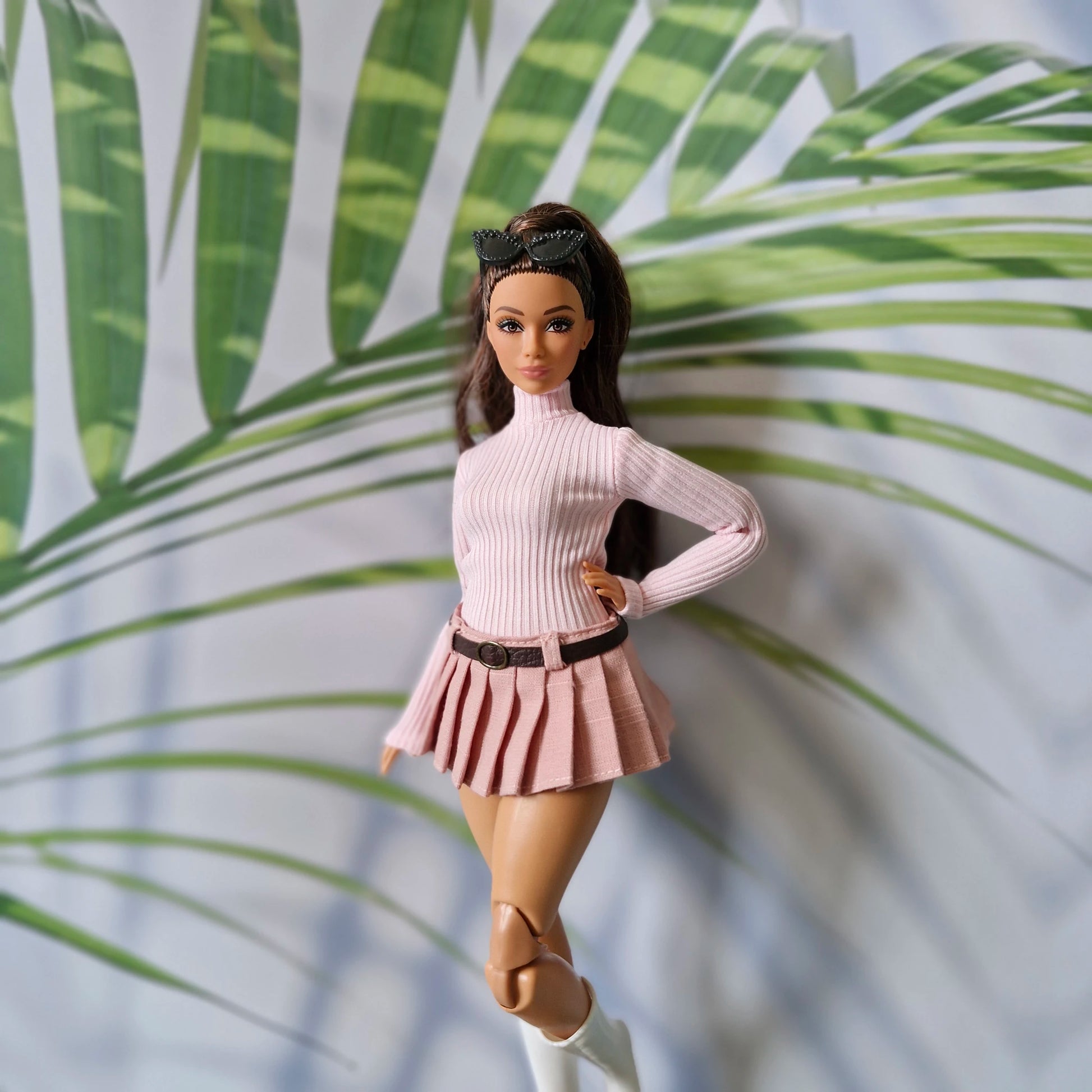 Brunette Curvy Barbie doll modeling a baby pink long sleeve turtleneck and dusty pink pleated skirt with belt