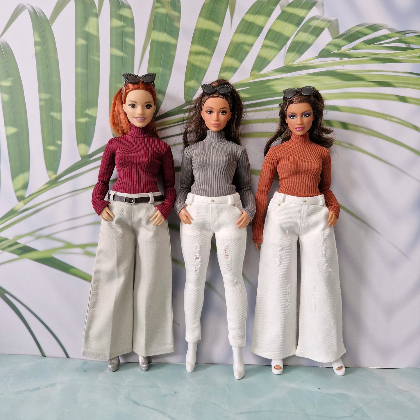Three Curvy fashion dolls posing in trendy ribbed sweaters and diverse white and beige trousers
