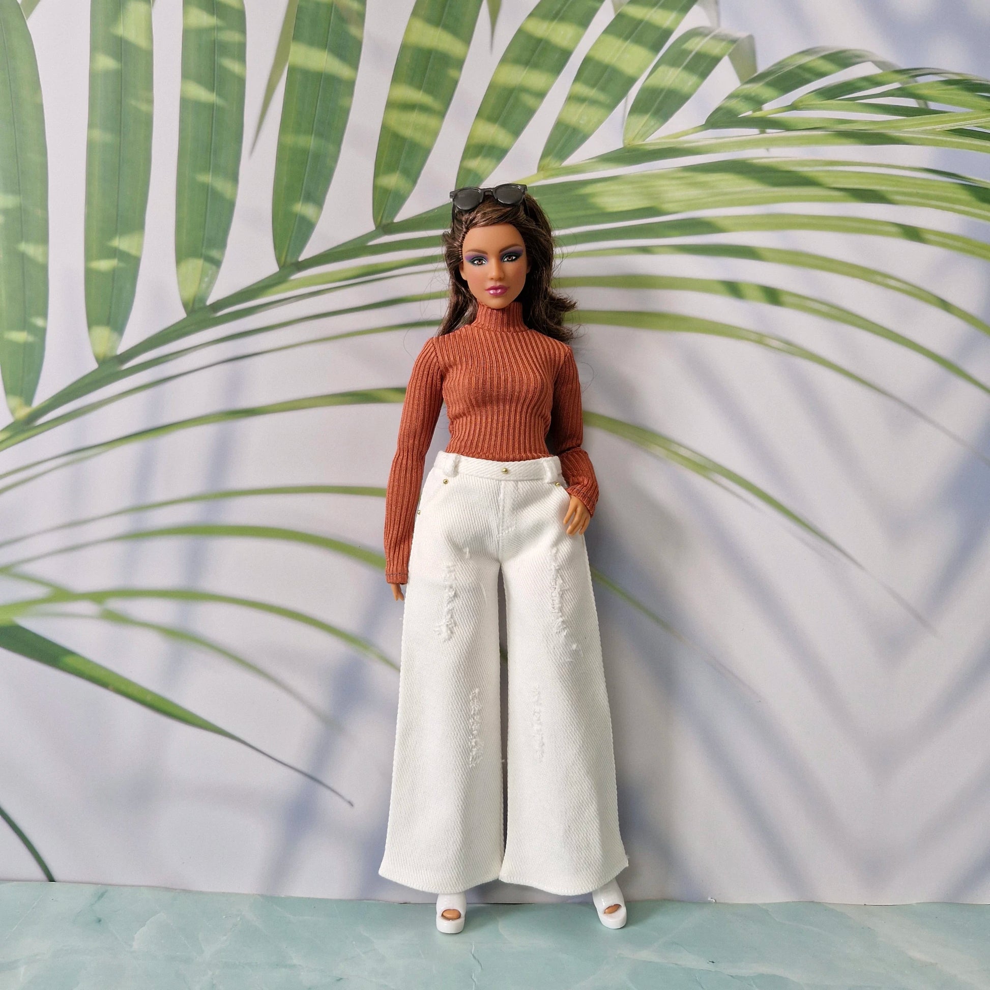 Curvy Barbie modeling a rust orange long sleeve top and white distressed wide-leg jeans