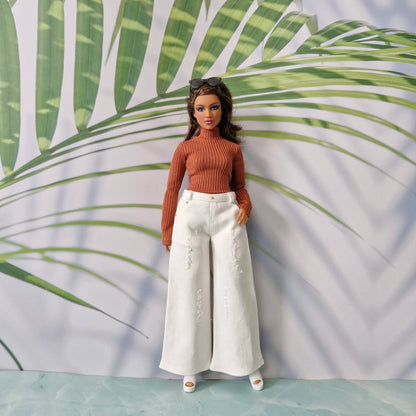 Curvy Barbie modeling a rust orange long sleeve top and white distressed wide-leg jeans