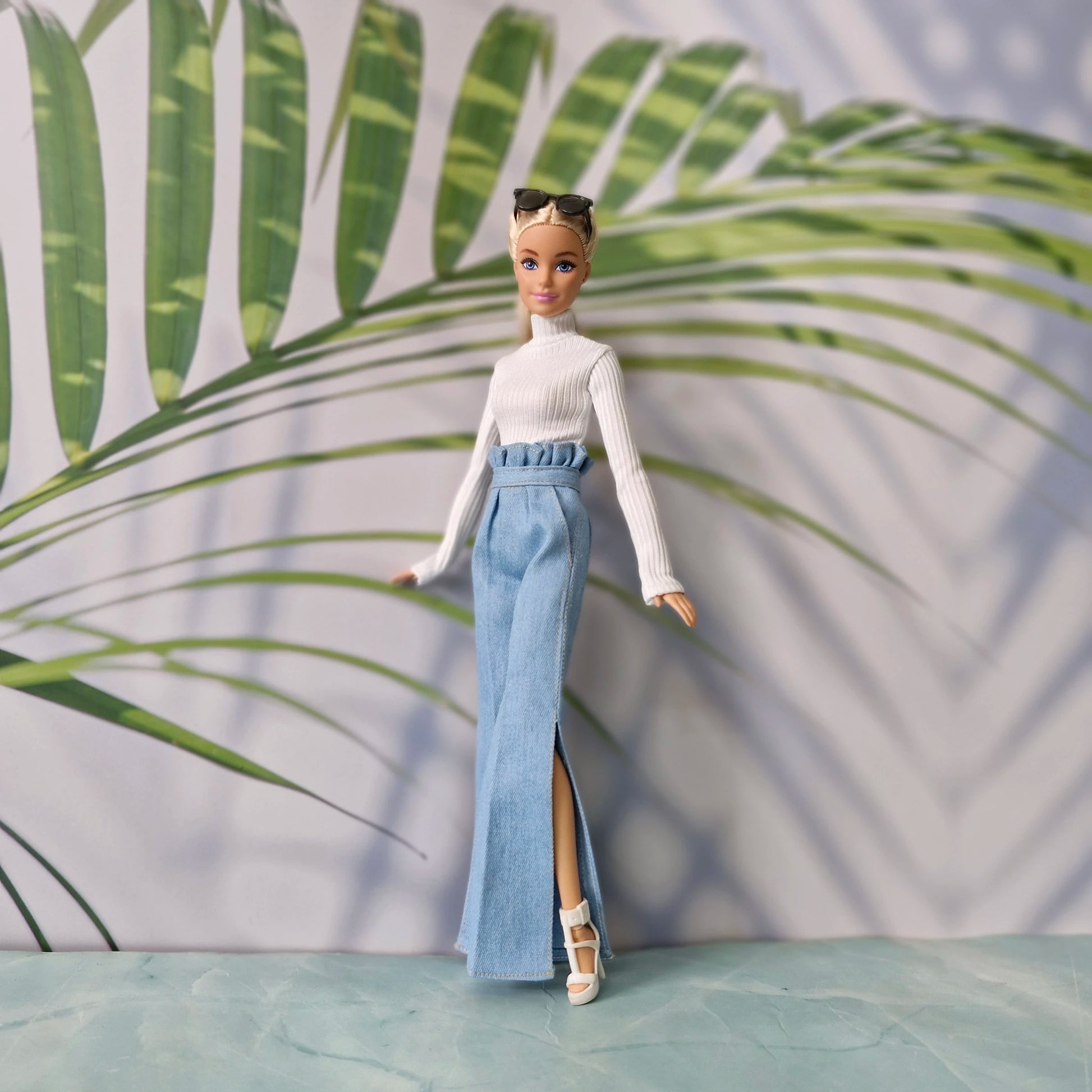 Blonde Barbie doll posing in trendy light wash jeans and white knit top outfit