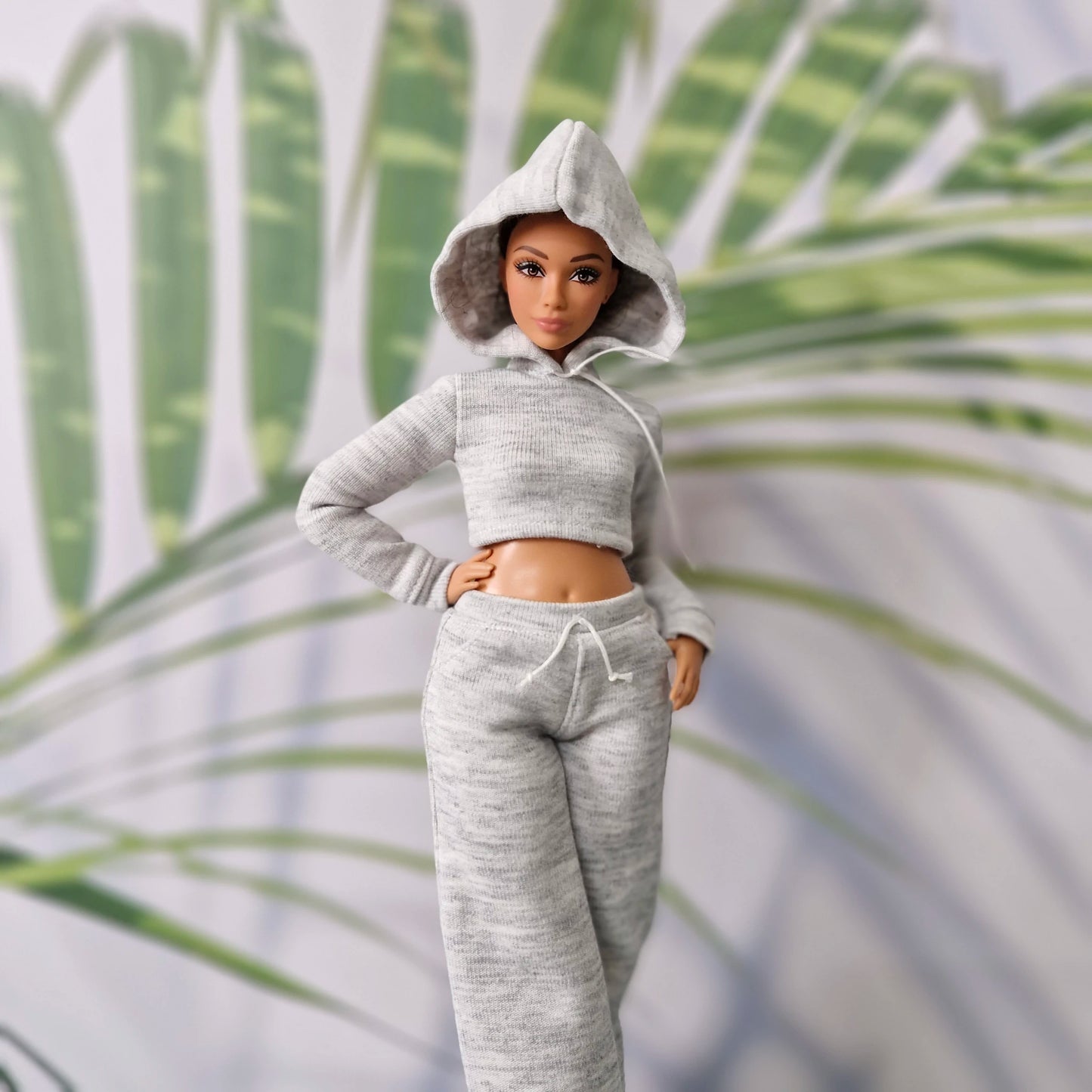 Barbie doll with hood up wearing a grey athletic hoodie and sweatpants