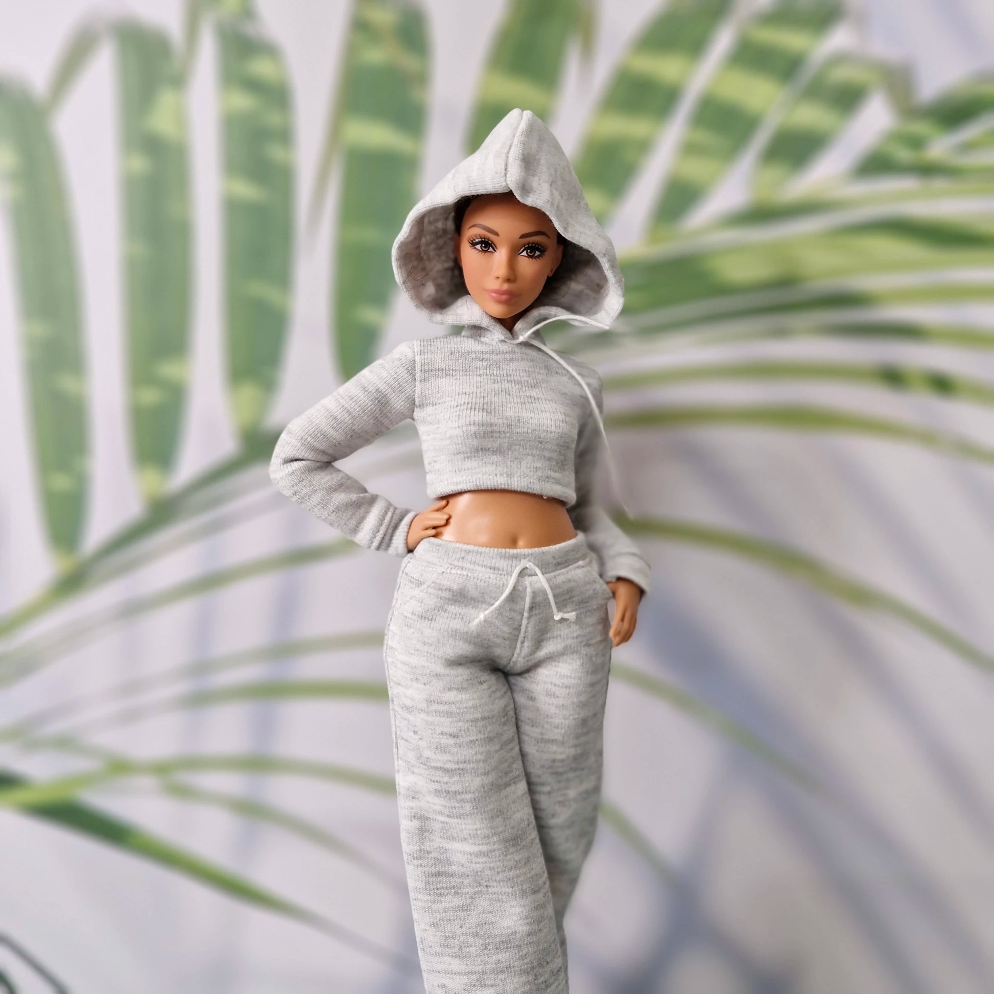 Barbie doll with hood up wearing a grey athletic hoodie and sweatpants