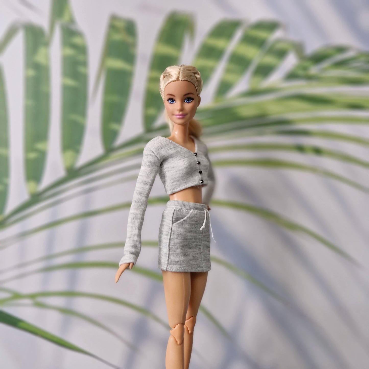 Close up of Barbie doll in grey knit long sleeve cardigan and skirt