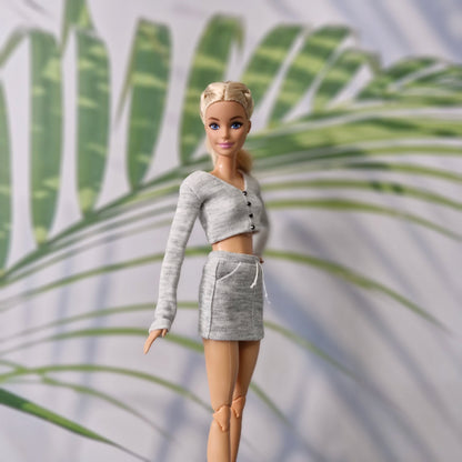 Close up of Barbie doll in grey knit long sleeve cardigan and skirt