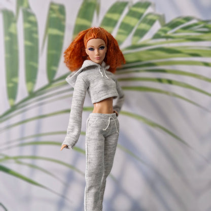 Barbie doll in a gray tracksuit with red hair against a leafy background