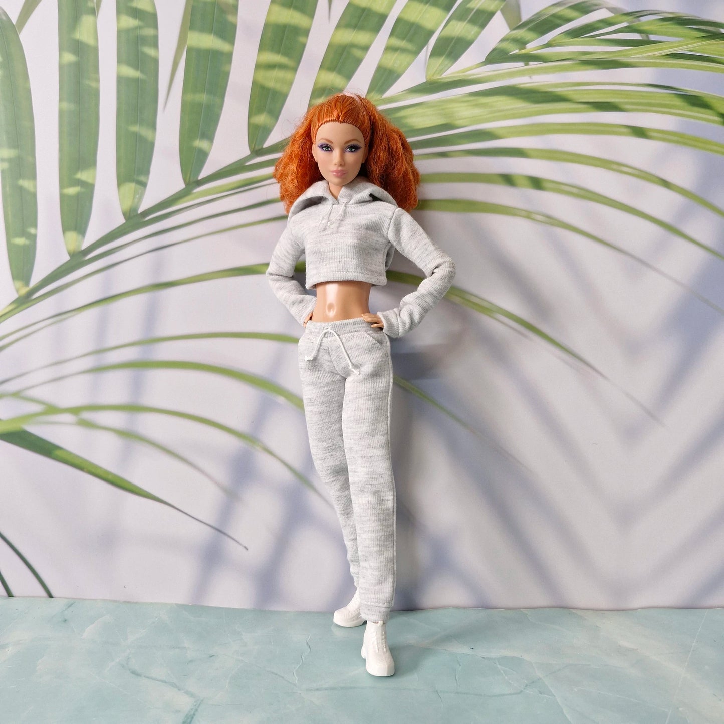 Redhead Barbie doll standing in grey athletic hoodie and jogger pants