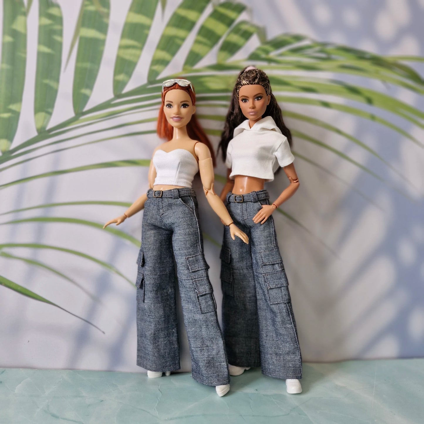 Standard and Curvy Barbie dolls posing in white tops and dark denim wide-leg cargo pants