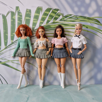 Group of four Barbie dolls including standard and curvy sizes wearing pleated mini skirts and various casual crop tops