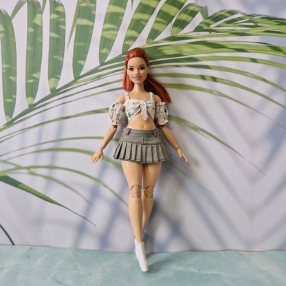 Curvy redhead Barbie doll wearing a floral off the shoulder crop top and olive green pleated skirt