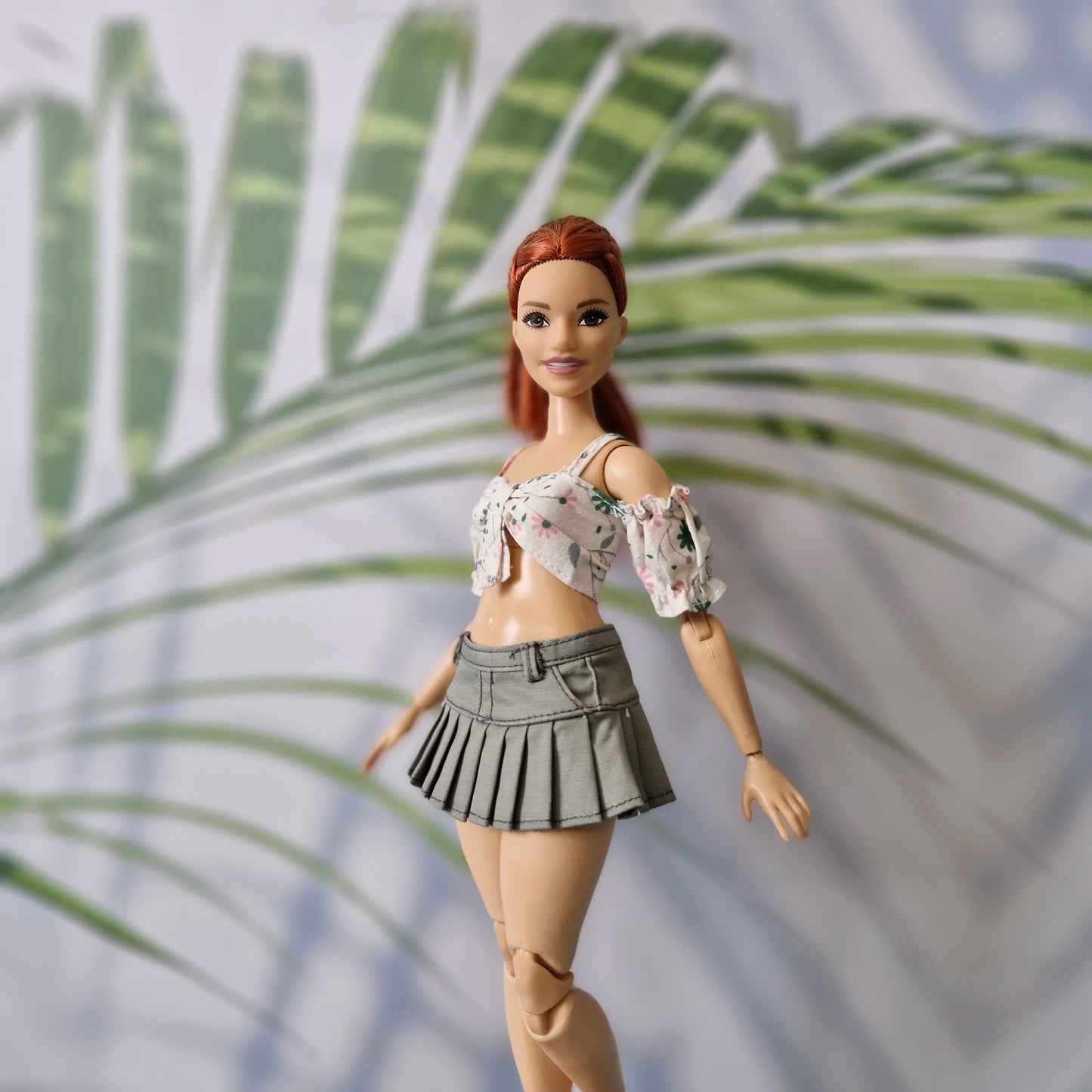 Close up of Curvy Barbie doll in a summer floral crop top and stylish olive pleated mini skirt