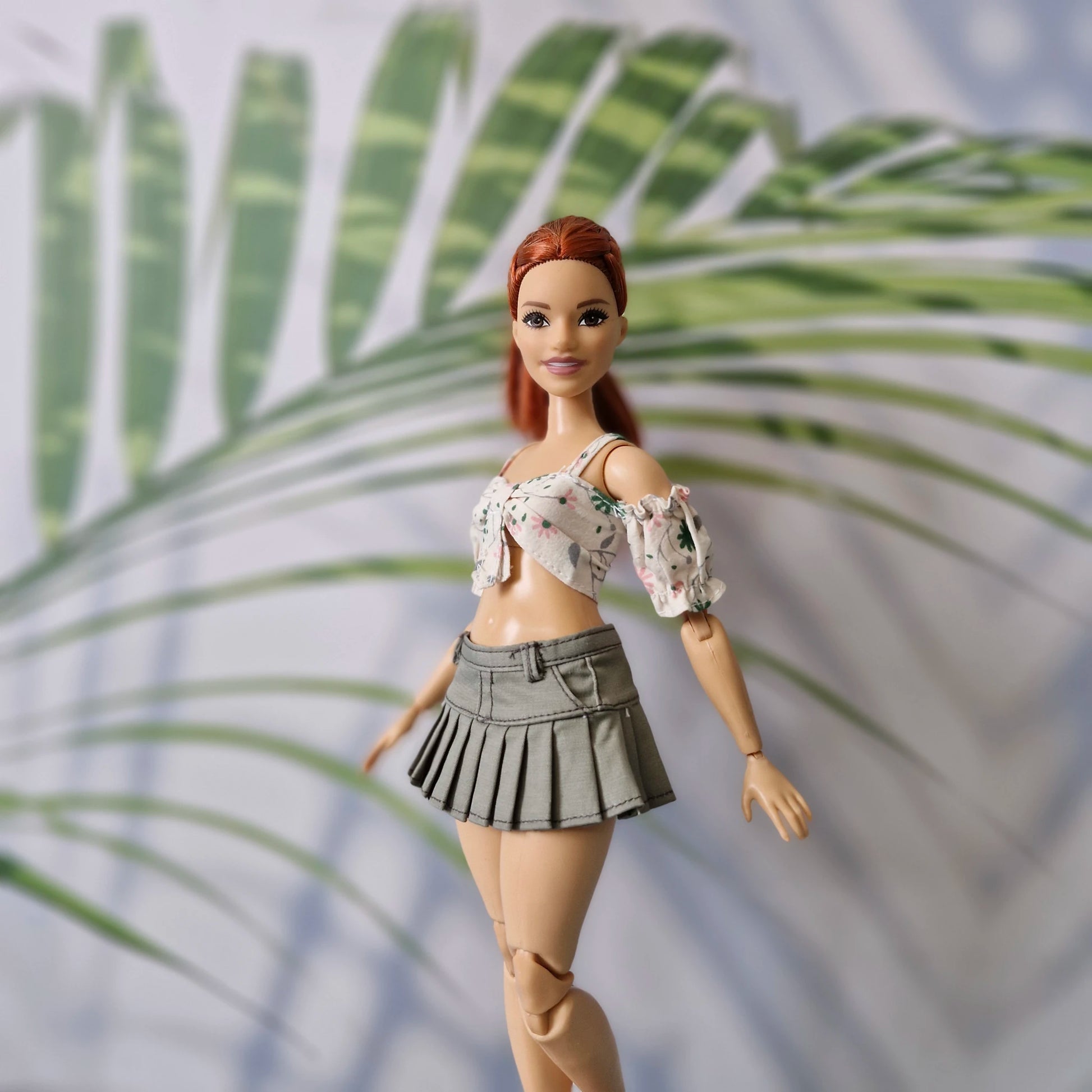 Close up of Curvy Barbie doll in a summer floral crop top and stylish olive pleated mini skirt