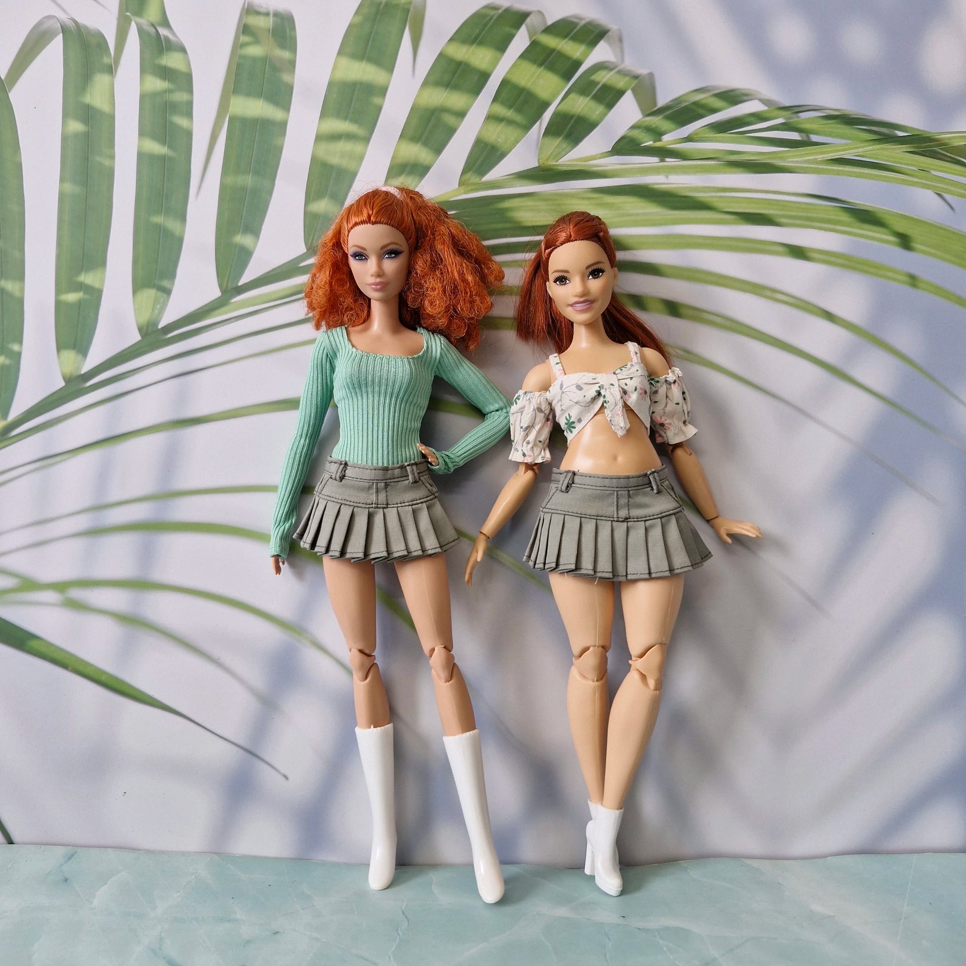 Two redhead Barbie dolls in standard and curvy sizes wearing olive green pleated skirts and crop tops