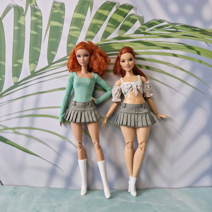 Two redhead Barbie dolls in standard and curvy sizes wearing olive green pleated skirts and crop tops