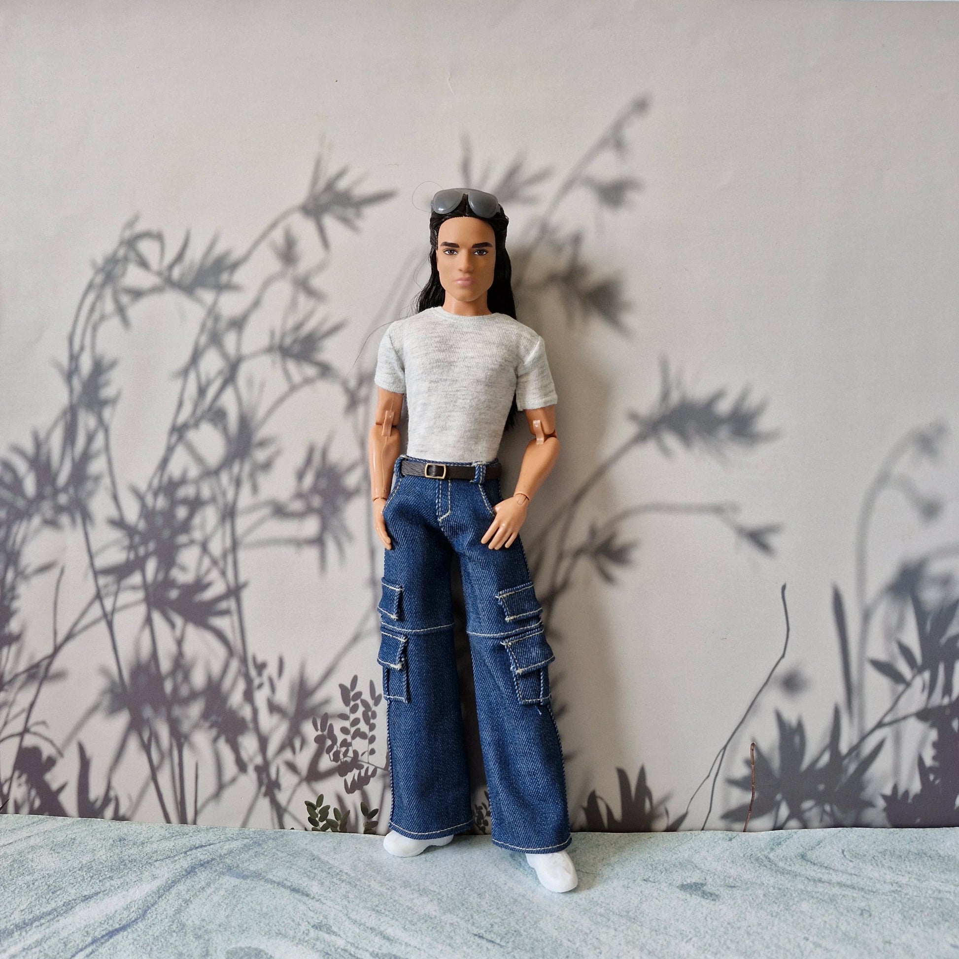 Full body shot of Ken doll wearing a grey t-shirt, blue denim cargo pants, and white sneakers