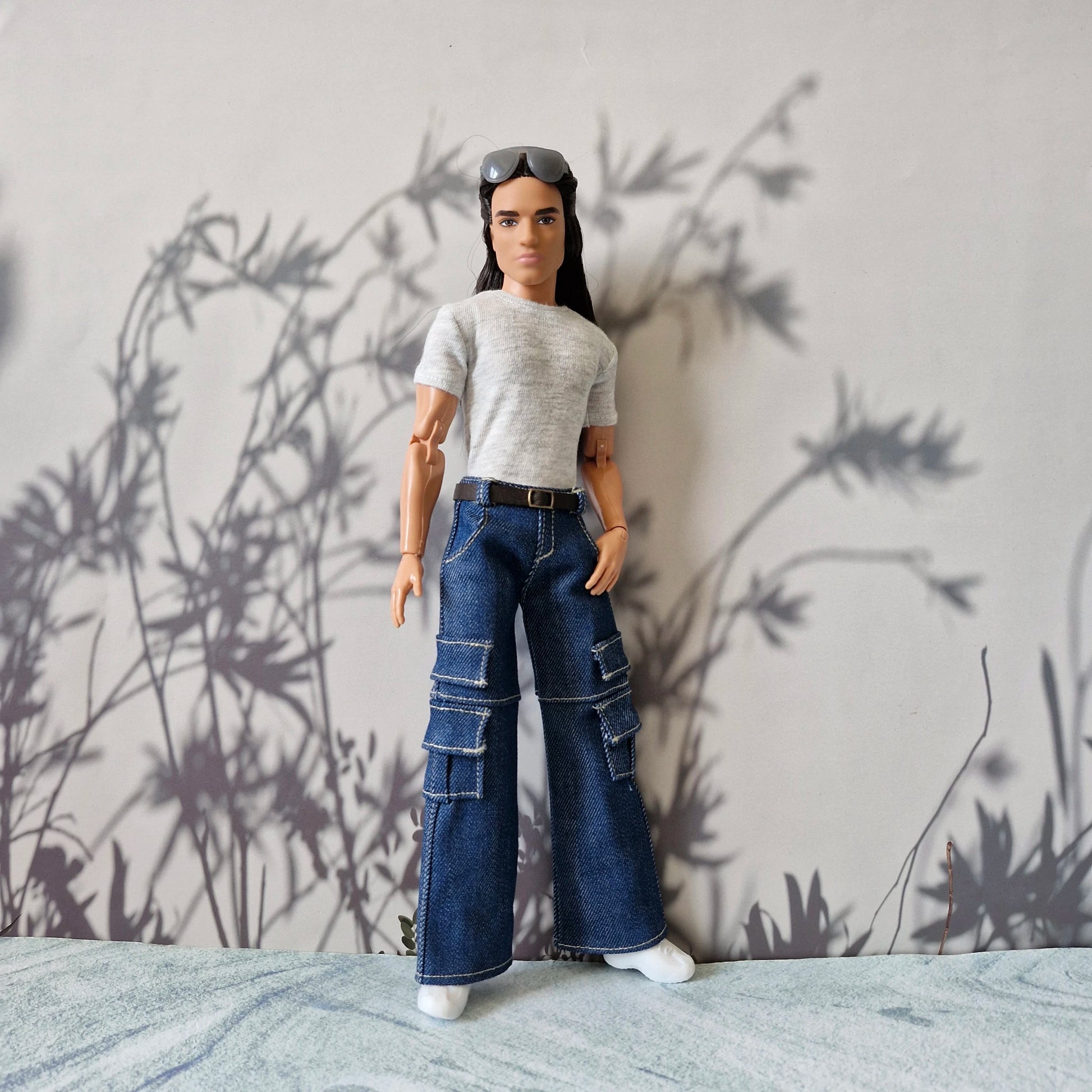 Ken doll posing in trendy streetwear including a grey t-shirt and baggy denim cargo pants