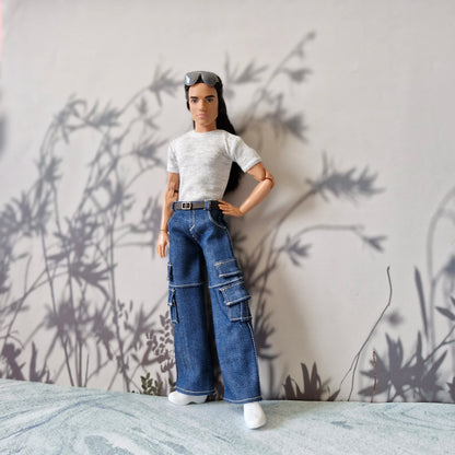 Action figure wearing a white t-shirt and blue jeans standing against a neutral background with plant shadows.