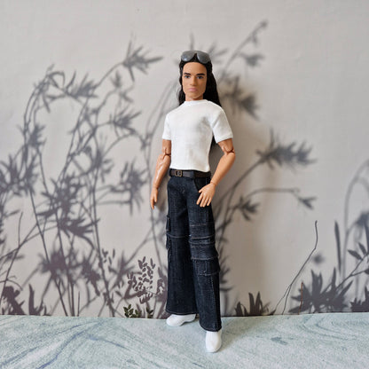Long-haired Ken doll posing in a white short-sleeve tee and dark baggy cargo jeans