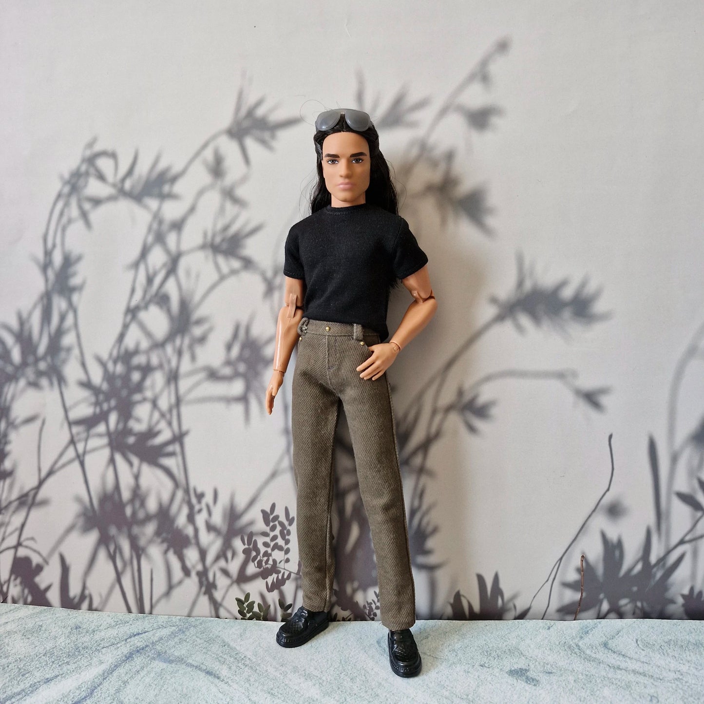 Ken doll modeling a classic black short sleeve t-shirt and tailored brown trousers