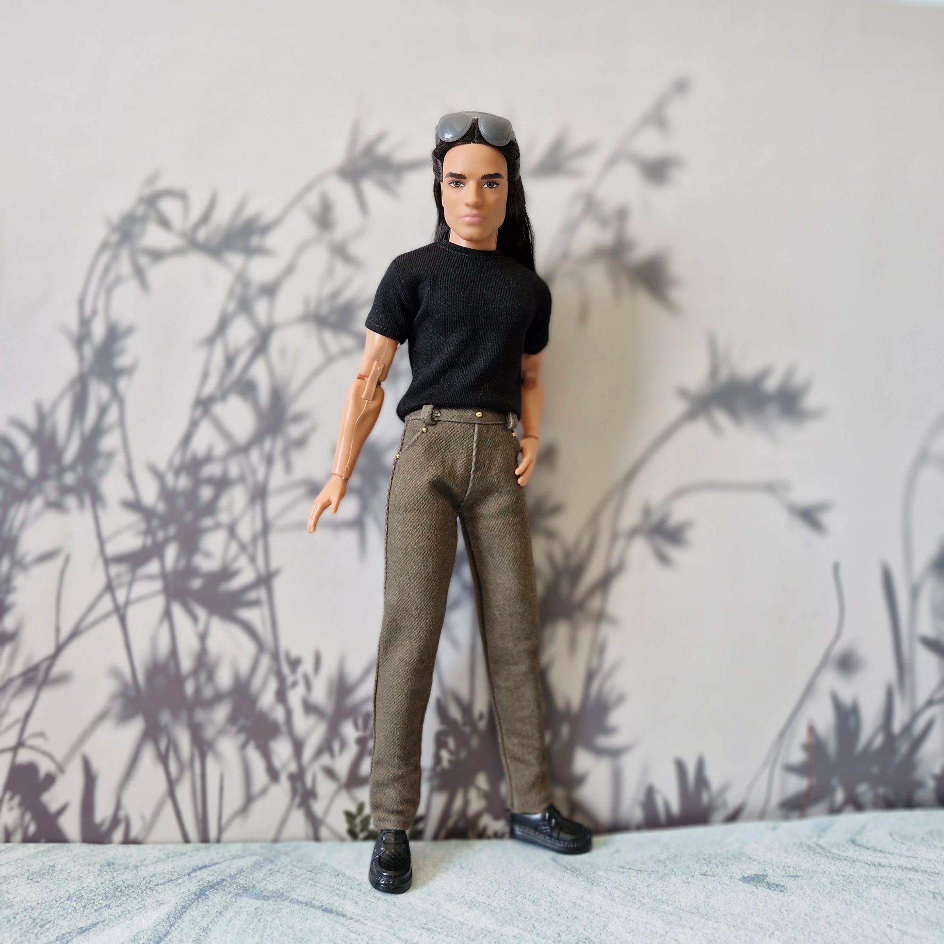 Front view of Ken doll dressed in everyday casual wear black tee and brown trousers