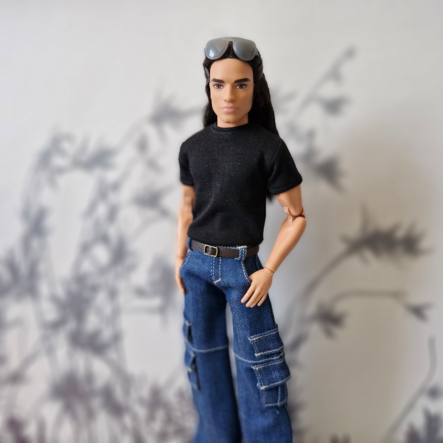 Ken doll standing with hands in pockets modeling a black tee and baggy blue cargo jeans
