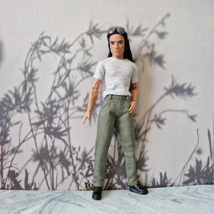 Full length shot of Ken doll standing in a grey t-shirt, olive green pants, and black shoes