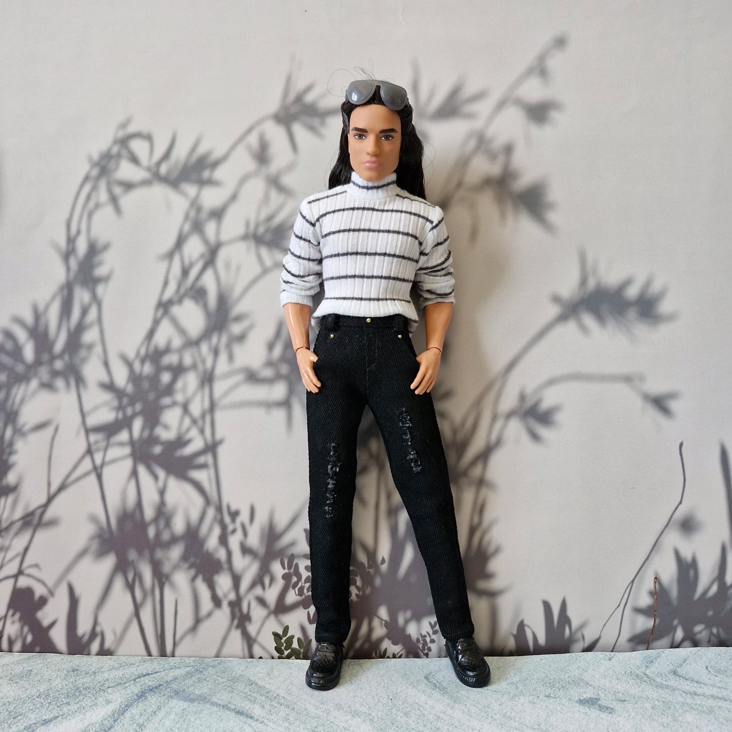 Full body shot of Ken doll wearing a trendy striped turtleneck and slim black distressed jeans