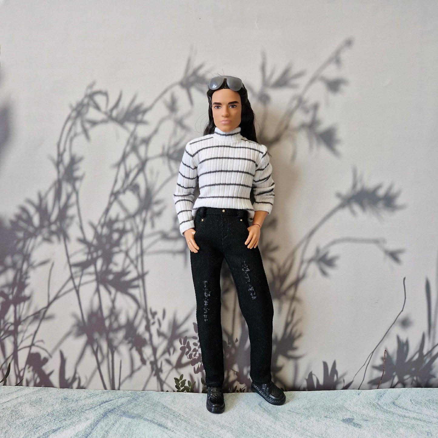 Ken doll wearing a black and white striped long sleeve turtleneck and black distressed jeans