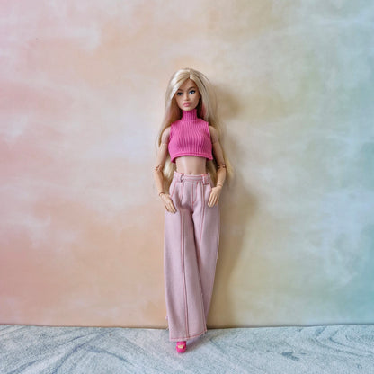 Barbie doll wearing a pink top and pants against a gradient background