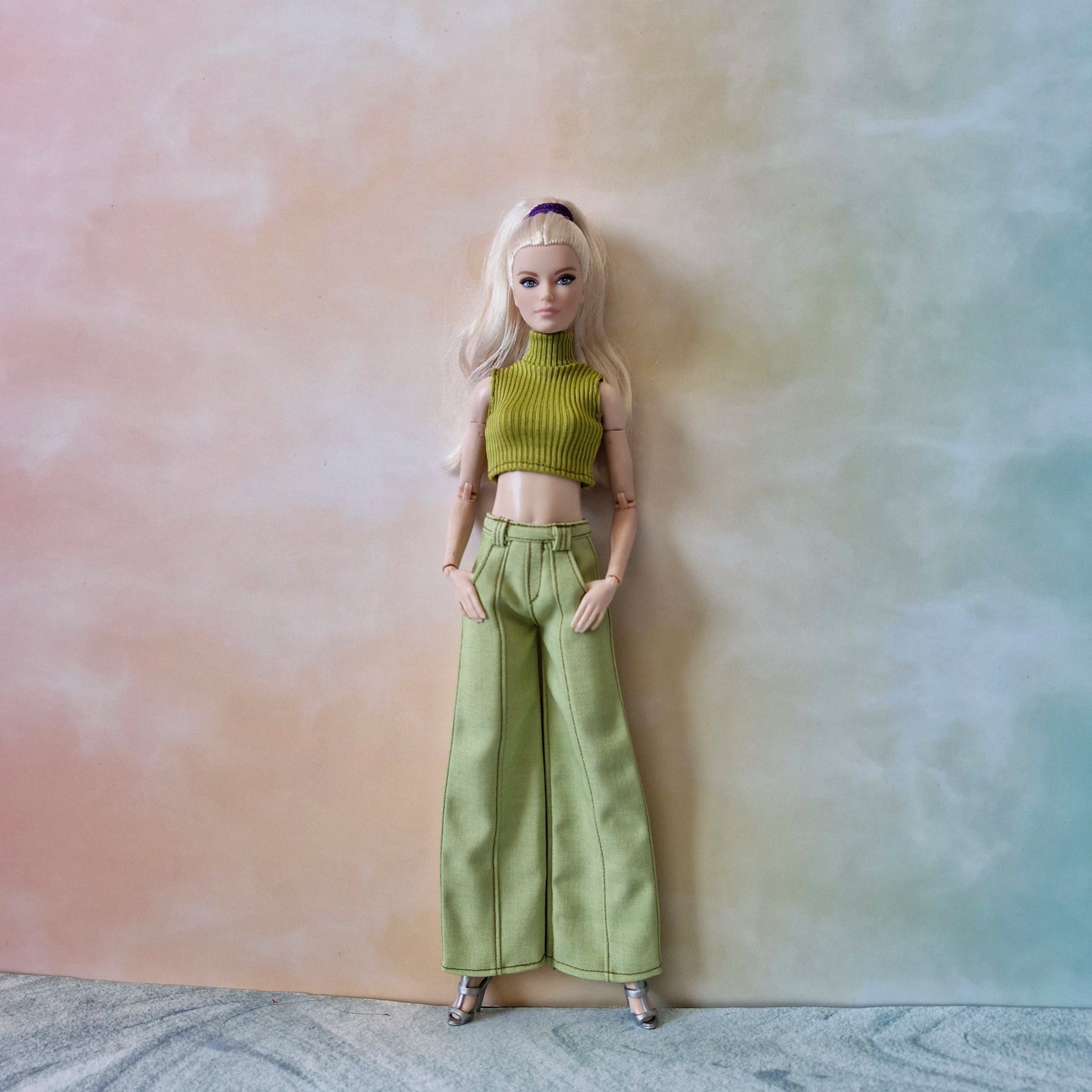 Blonde Barbie doll standing in an olive green ribbed turtleneck top and matching green pants