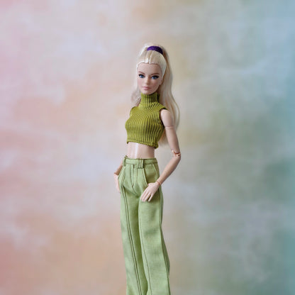 Barbie doll wearing a green outfit against a soft, multicolored background
