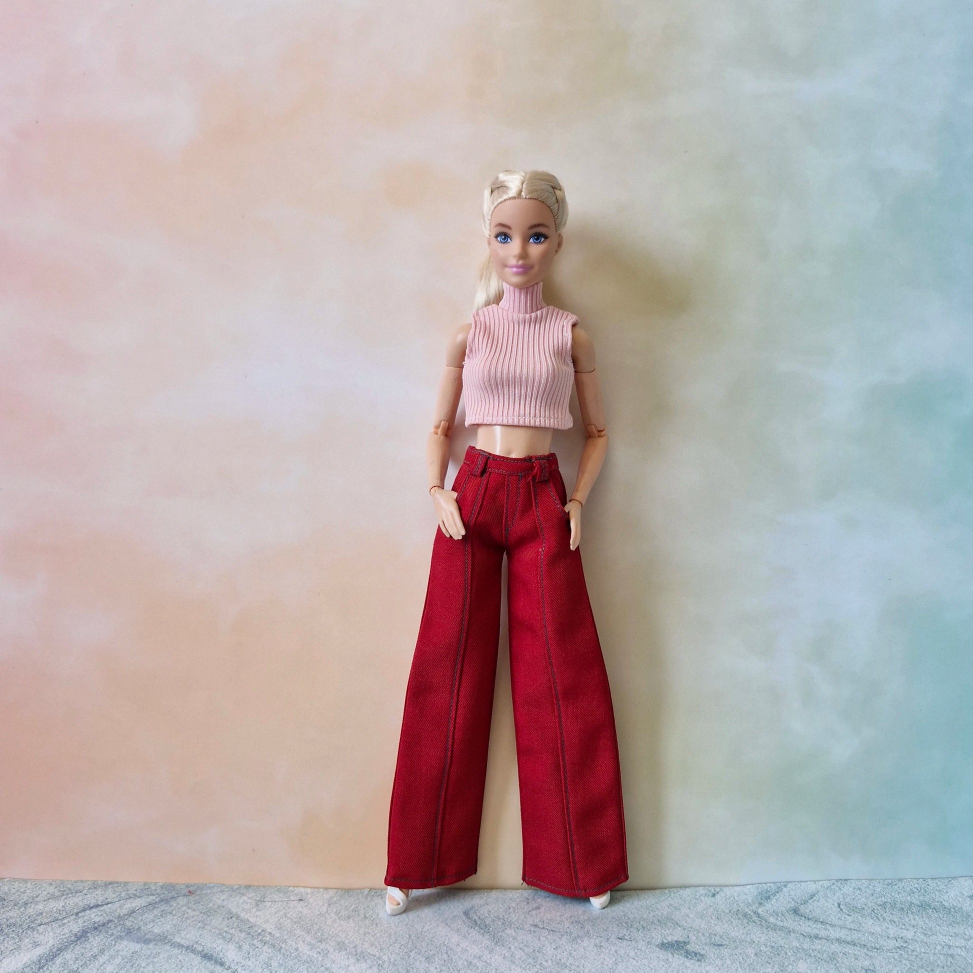 Blonde Barbie doll dressed in a light pink ribbed top and dark red wide-leg trousers