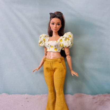 Curvy Barbie doll wearing mustard yellow bell bottom pants and floral puff sleeve crop top