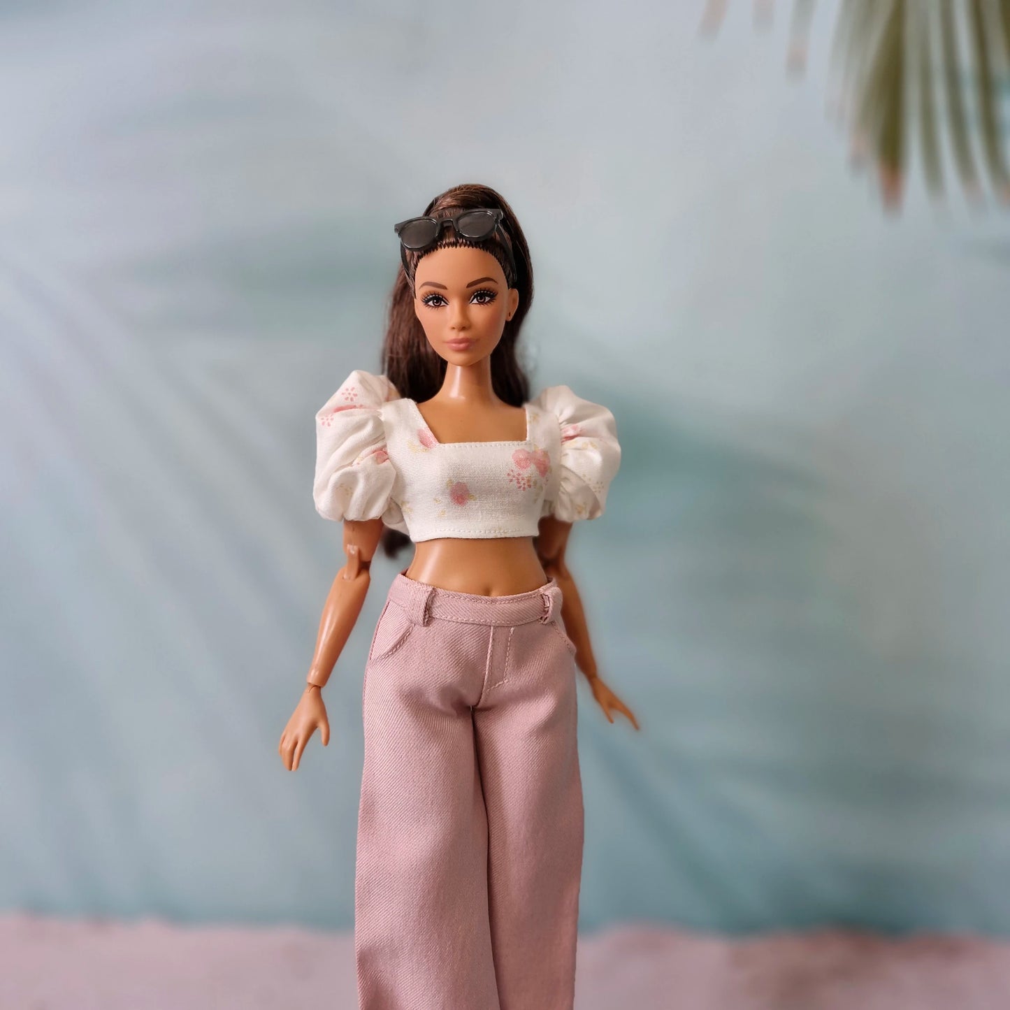 Close up of fashionable summer outfit for Curvy Barbie showing a pink floral puff sleeve shirt and pink high-waisted pants.