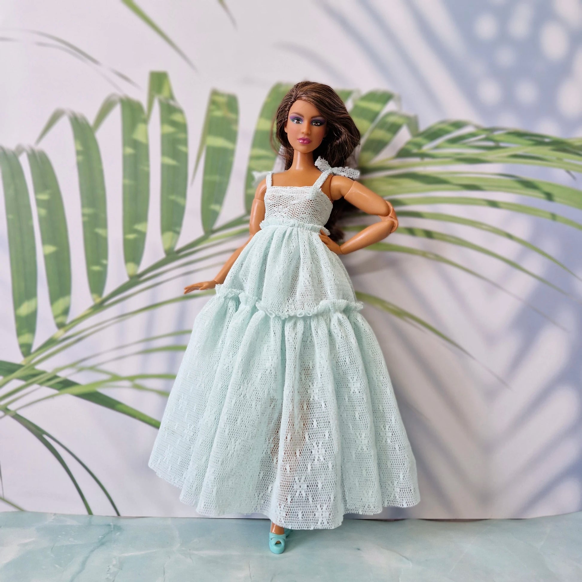 Brunette Barbie doll wearing mint lace tiered maxi dress with tropical leaf background
