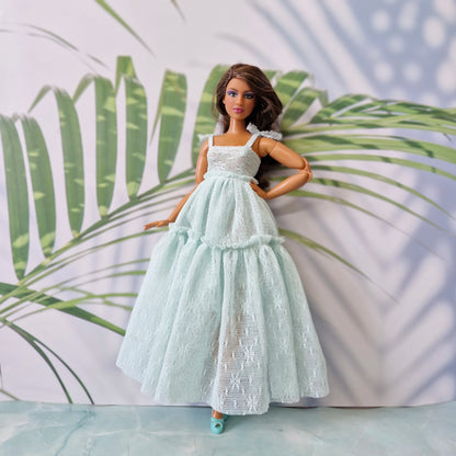 Brunette Barbie doll wearing mint lace tiered maxi dress with tropical leaf background