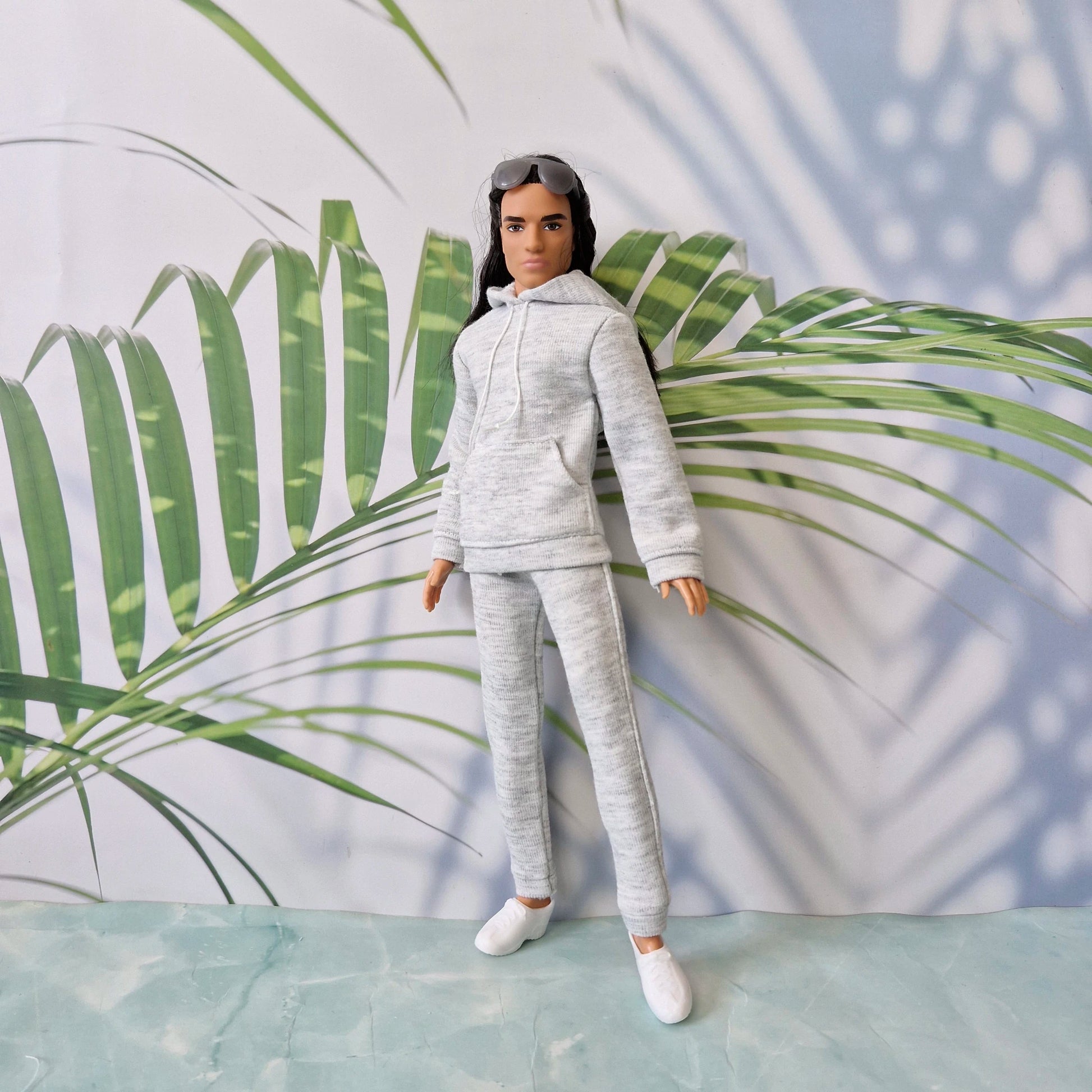 Detailed view of a Ken doll wearing a grey miniature sweatshirt and sweatpants, looking stylish and relaxed.