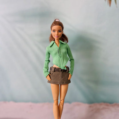 Barbie doll wearing a trendy green pointed hem shirt and an olive belted mini skirt.
