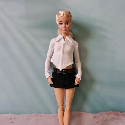 Barbie doll showcasing a classic white pointed hem collared shirt and black belted mini skirt.